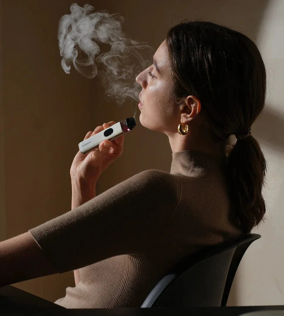 Woman using a vape device with smoke in a dimly lit room Vaporesso XROS 5 30W Pod Kit